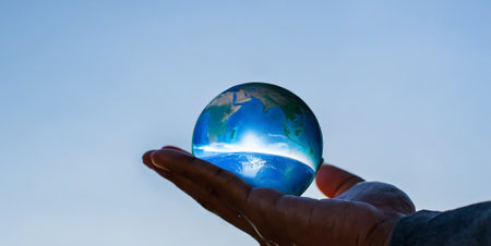Globe in human hand on blue sky background. Global warming conceptの素材