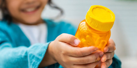 Close-up of a child holding a bottle of vitamins in her handsの素材