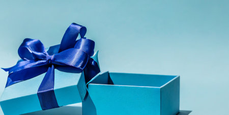 Blue gift box with blue ribbon on blue background. Holiday concept.の素材