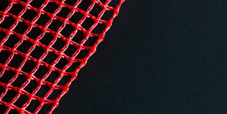 Red netting on black background. Close up. Copy space.の素材