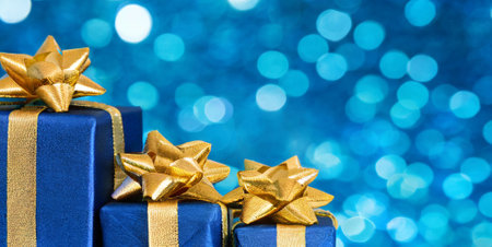 Gift boxes with gold bow on blue bokeh background.の素材