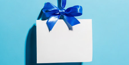 close up of a gift tag with blue ribbon bow on blue backgroundの素材