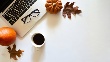 Flat lay of workspace with coffee cup, pumpkins and autumn leaves on white backgroundの素材