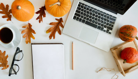 Flat lay of workspace with pumpkins, coffee and notebook on white backgroundの素材