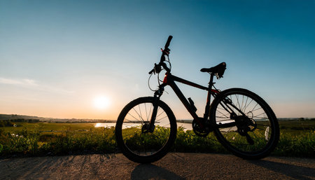 Silhouette of mountain bike at sunset time with lake background.の素材