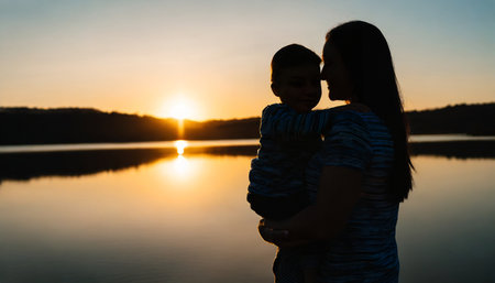 Silhouette of a mother and baby on the lake at sunsetの素材