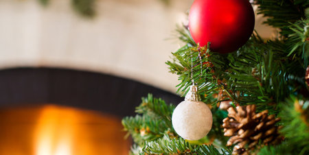 Christmas tree with red and white baubles in front of fireplaceの素材