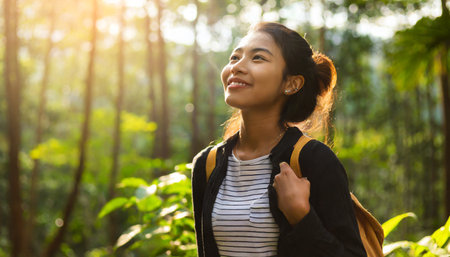 portrait of asian woman with backpack smiling in the forest.の素材