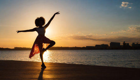 Silhouette of a young girl dancing on the beach at sunsetの素材