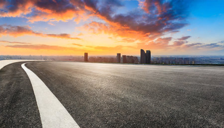 round asphalt road and city skyline with colorful sky clouds at sunsetの素材