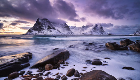 rocky beach in winter during sunset magical north landscape sea coast with stones blurred water snowy rocky mountains purple sky with clouds at dusk uttakleiv beach in lofoten islands norwayの素材