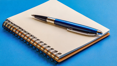 Notebook and pen on a blue background, business and education conceptの素材