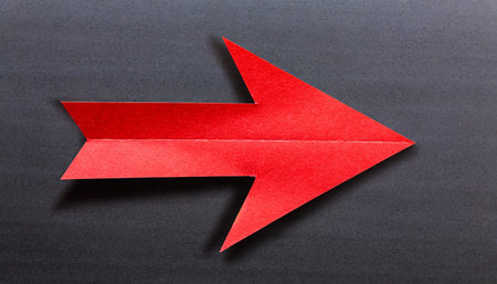 Red paper arrow on black background, business and finance concept idea.の素材