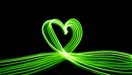 long exposure light painting photography vibrant neon green heart symbol shape love and romance concept against a black backgroundの素材