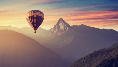 hot air balloon above high mountain at sunset filtered backgroundの素材