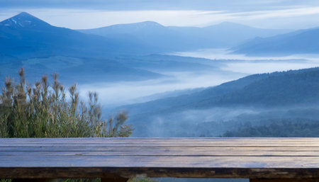in the misty morning landscape you can admire a wooden table against the backdrop of a blurred mountain view the cool sensation in blue hues adds to the overall ambianceの素材