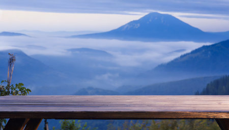 in the misty morning landscape you can admire a wooden table against the backdrop of a blurred mountain view the cool sensation in blue hues adds to the overall ambianceの素材