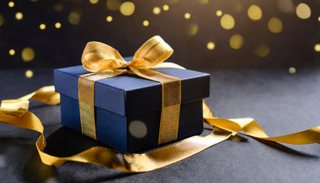 dark blue gift box with elegant gold ribbon on dark background greeting gift with copy space for christmas present holiday or birthdayの素材