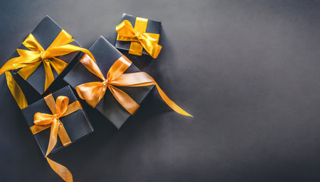 dark gift boxes with satin ribbon and bow on black background holiday gift with copy space birthday or christmas present flat lay top view christmas giftbox black friday conceptの素材