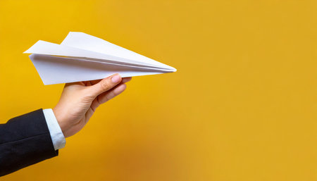 hand holding paper plane over yellow background panoramic mock up imageの素材