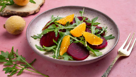 seasonal vitamin salad orange beetroot and arugula in plate on pink background diet healthy eating conceptの素材