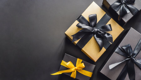 dark gift boxes with satin ribbon and bow on black background holiday gift with copy space birthday or christmas present flat lay top view christmas giftbox black friday conceptの素材