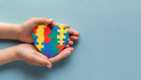 world autism awareness day concept adult and child hands holding puzzle heart on light blue backgroundの素材