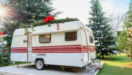 festive camper trailer with christmas tree background sets the scene for a merry holiday celebrationの素材