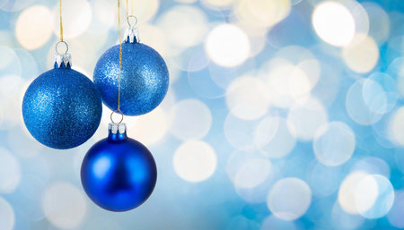 three blue christmas bauble balls hanging in front of bokeh background with copy space christmas or new year templateの素材
