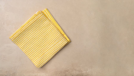 striped textile yellow serving napkin on beige plastered backdropの素材