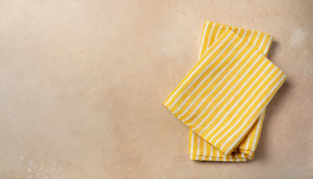 striped textile yellow serving napkin on beige plastered backdropの素材