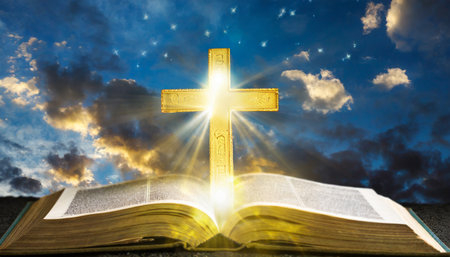 illuminated cross on a holy bible with a dramatic background skyの素材