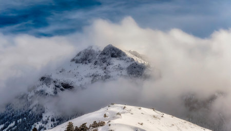 snowy mountain summit blanketed in thick winter snow and cloudsの素材