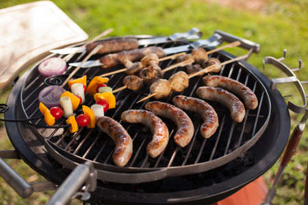 Fresh meat sausage and vegetables grilled at a summer weekend barbecueの写真素材