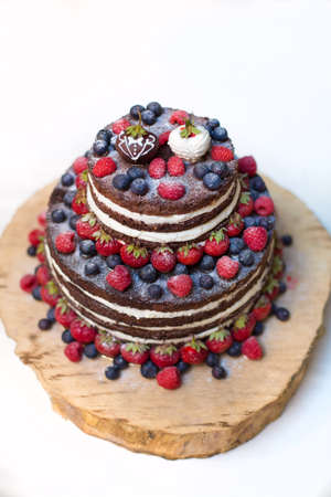 Chocolate cake cake with raspberry and strawberry blackberry on a wooden plateの写真素材