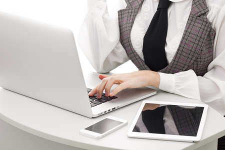 Close-up on arms of confident business woman working on laptop tablet and phone, selective focusの写真素材