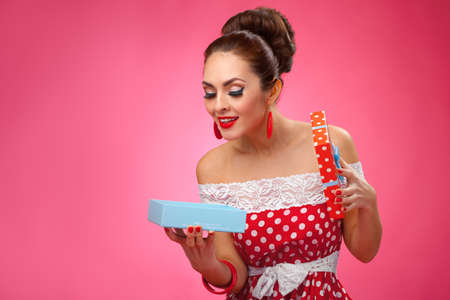 Funny portrait of a smiling cute young female model holding many shopping bags in her arms wearing red dressの写真素材