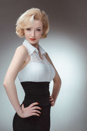 Pin-up girl, 50 style. Studio shot of young and beautiful woman wearing white blouse and black fitting, in studio. Professional makeup and hair styleの写真素材