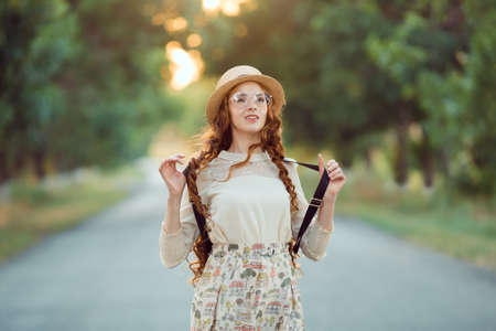 Young girl traveler enjoy the travel on foot. Portrait of happy woman walking with hat and backpack on the road. Adventure is coming conceptの写真素材