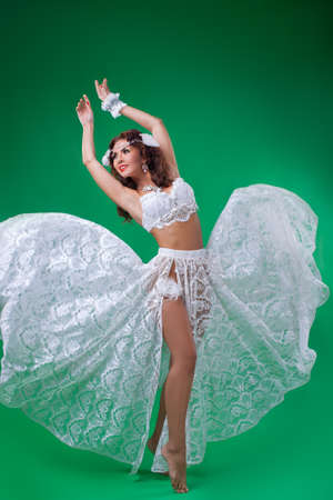 Women in carnival white dresses.Full length portrait of beautiful girl in studio against green backgroundの写真素材