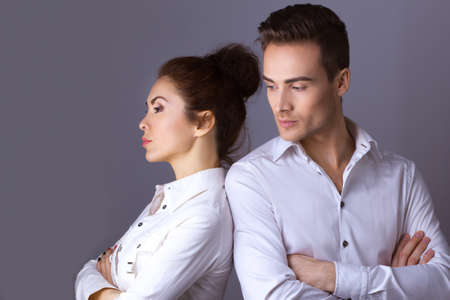 Unhappy couple not talking after an argument against gray background