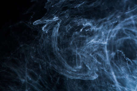 Abstract acrylic paint swirls in water on black backgroundの写真素材