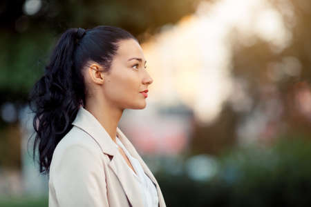 Woman smiling - side view portrait of happy lovely and beautiful mixed race asian caucasian young businesswoman in casual clothes outdoor in the city parkの写真素材