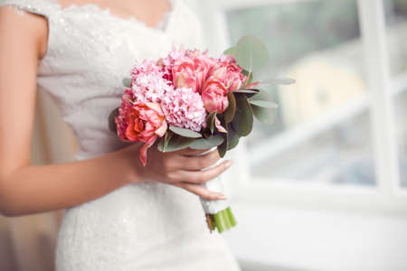 Bridal bouquet Beautiful of pink wedding flowers in hands of the bride. Close-up interior studio...