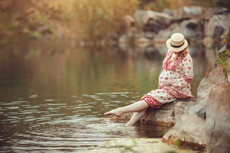 Pregnancy and Nature concept. New life. Pregnant woman resting on the riverの写真素材