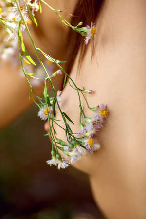 Spring wild flowers and naked beautiful breast close-up. Tender nature and woman bodyの写真素材