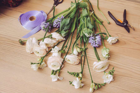 Beautiful flowers and florist equipment on wooden tableの写真素材