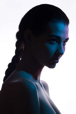 Art fashion studio portrait of nude elegant woman on white background. Profile of attractive mixed race Asian Caucasian female model with braid. Perfect slim body. Wild aggressive lookの写真素材