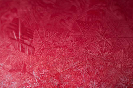 Christmas and New Year Holidays precious backdrop. Frozen snow globe christmas magic ball with flying snowflakes. Winter Background with copy space close-up. Macro shot of ice patterns frosted on ball of soap against red abstract bokeh background.の写真素材