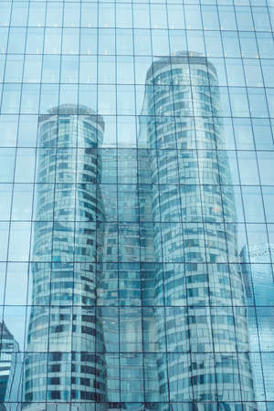 Modern business building reflection in windows of other skyscraper. Modern business office building exterior. Business concept.の写真素材